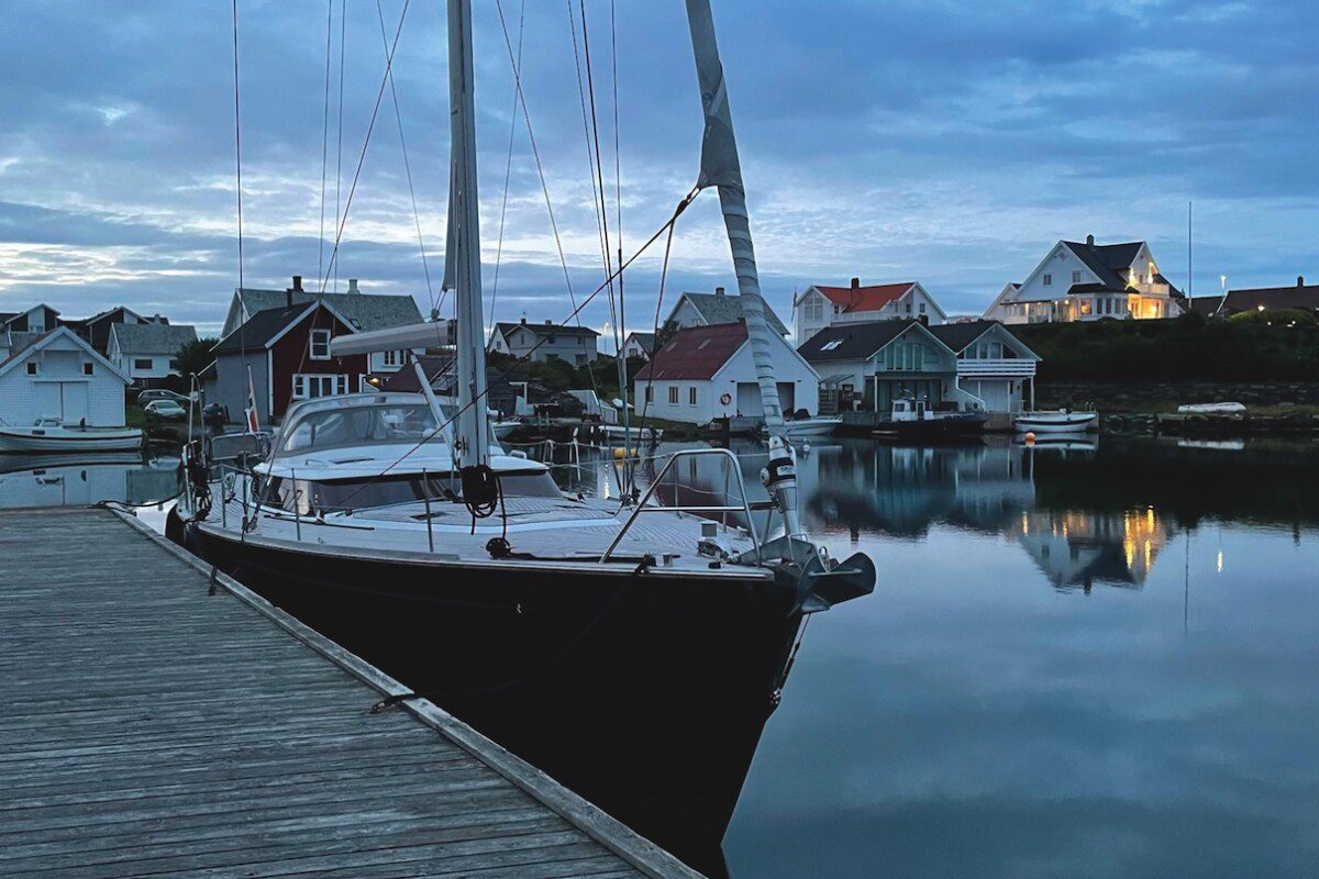 Blue sailing yacht tied up to a pontoon in quiet harbour at dusk