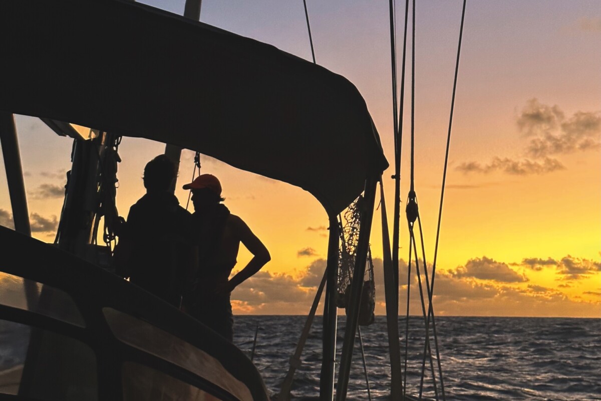 Silhouette of two people on the deck of a sailing yacht at sunset