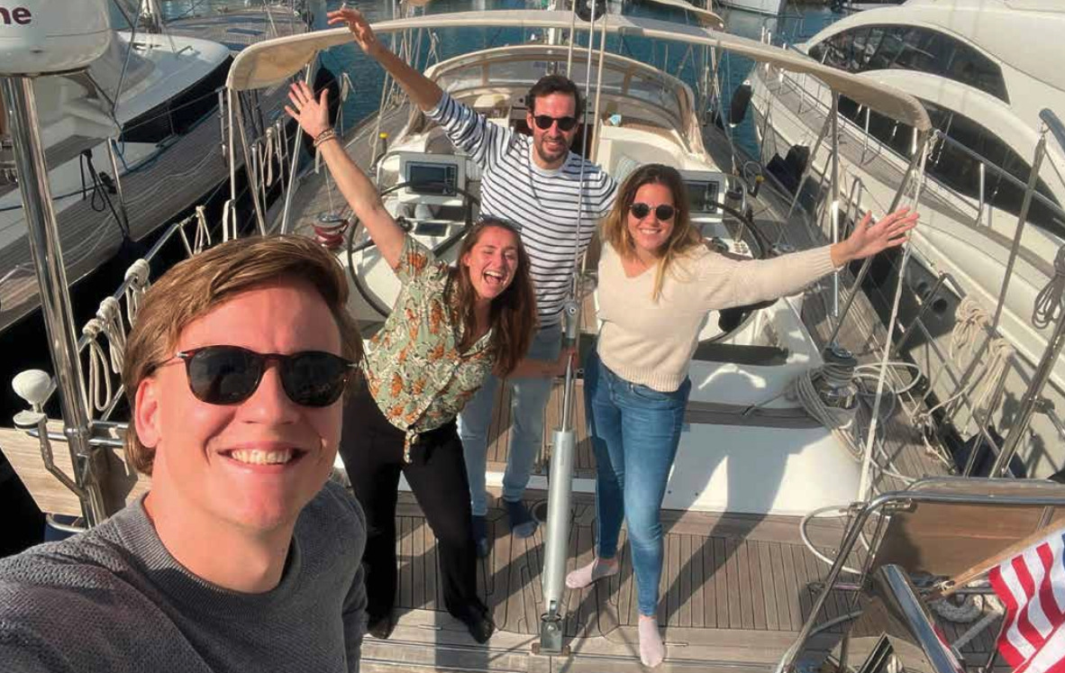 Four young people in jeans on the deck of a sailing boat